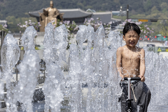 A child cools off from the heat at a fountain in Gwanghwamun Square in central Seoul on Sunday, as midday highs reached as high as 29 degrees Celsius (84 degrees Fahrenheit) in the capital. [JUN MIN-KYU]