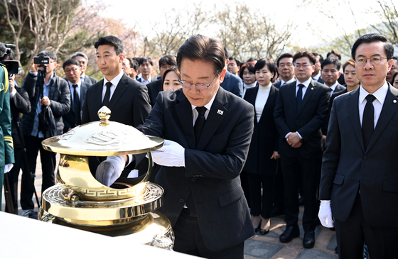 DP Chairman Lee Jae-myung, center, pays his respects at former President Kim Dae-jung’s grave at Seoul National Cemetery in Dongjak District, southern Seoul, joined by newly elected lawmakers of the DP and its satellite party on Friday following their general election victory. [JOINT PRESS CORPS]
