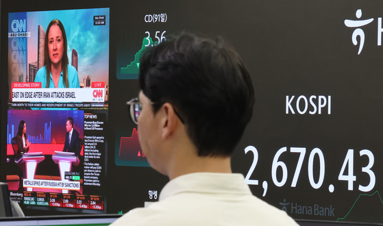 The Kospi closed down 0.42 percent from the previous trading day on Monday amid intensified geopolitical tension in the Middle East. Electronic displays at Hana Bank in central Seoul show the Kospi and news on the Middle East. [YONHAP]