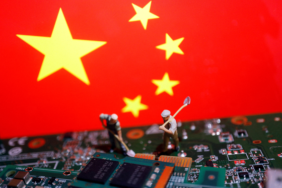 Miniature workers are placed on printed circuit boards with semiconductor chips with the flag of China in the backdrop, in this illustration picture taken July 5, 2023. [REUTERS/YONHAP]