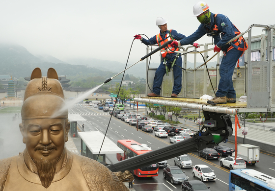 Seoul city workers clean the dust off of the statue of King Sejong in Gwanghwamun, central Seoul, on Tuesday morning. Due to the recent yellow and fine dust sweeping the country, the cleaning procedure was carried out in four stages. [JOINT PRESS CORPS]