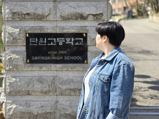 Yu Ga-young, a former Danwon High School student who survived the deadly accident, looks at the nameplate of Danwon High School in Ansan, Gyeonggi. [SON SUNG-BAE]
