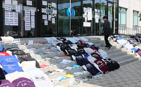 Pukyong National University varsity jackets are laid down in front of the university's administration building in Nam District, Busan, in March, in protest of the university's decision to merge with Korea Maritime & Ocean University. [JOONGANG ILBO]