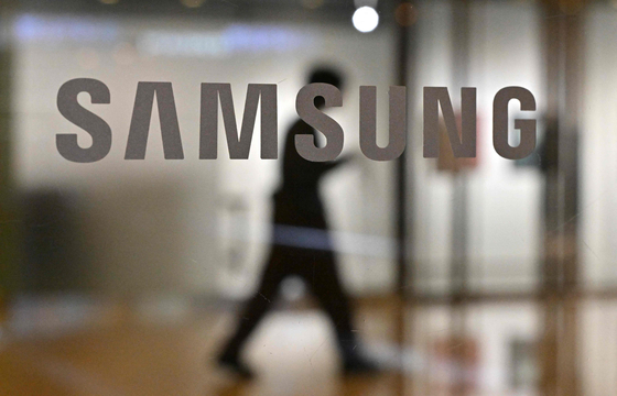 A man walks past the Samsung logo displayed on a glass door at the company's Seocho building in Seoul. [AFP]