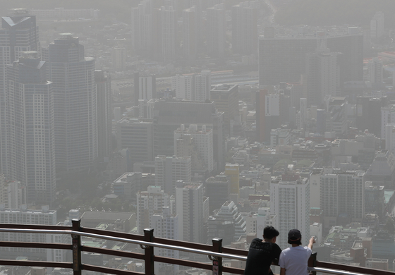 People look out over a hazy Busan from an observatory on Hwangnyeongsan, a mountain in the city, as the fine dust concentrate levels in the area hit the “very bad” level for a second day due to yellow dust. Rainfall over the weekend is expected to clear the air. [NEWS1]