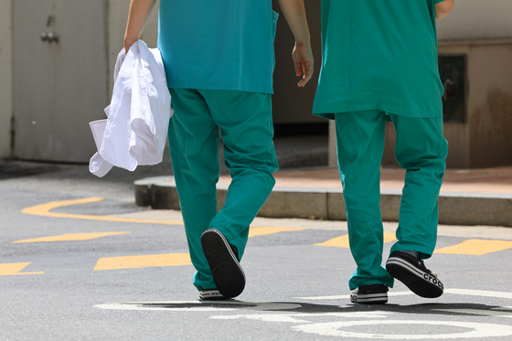 Two medical professionals walk in a general hospital's compound on Thursday in Seoul. [YONHAP] 