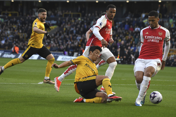 Wolverhampton Wanderers' Hwang Hee-chan, center, challenges for the ball with Arsenal's William Saliba, right, during a Premier League match at the Molineux in Wolverhampton, England on April 20.  [AP/YONHAP]