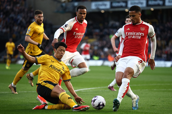Wolverhampton Wanderers' Hwang Hee-chan, left, vies with Arsenal's William Saliba at the Molineux in Wolverhampton, England on Saturday. [AFP/YONHAP]