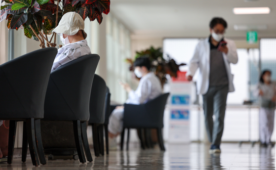 A medical professional passes by resting patients at a hospital in Seoul on Sunday. [YONHAP]