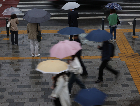 People walk with their umbrellas near the Seoul City Hall in Jung District, central Seoul, on Wednesday morning. [YONHAP]