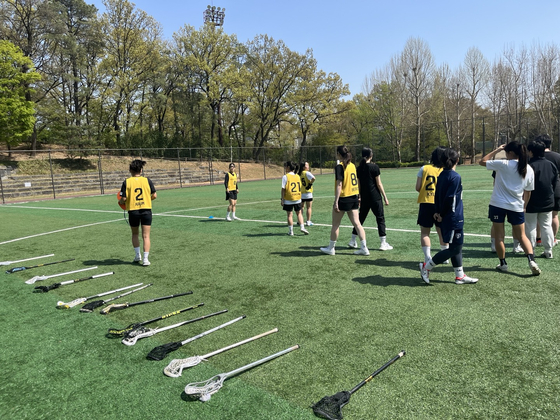 Players put down their lacrosse sticks in a line and head to warmups. Neat. [MARY YANG]
