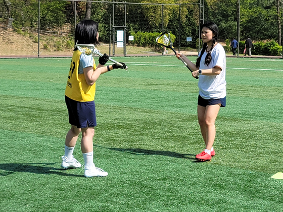 A confused Mary, right, concentrates on learning proper passing technique from a patient Kyu-min. [MARY YANG]