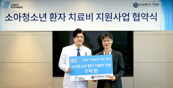 JYP Entertainment Vice President and Chief Financial Officer Byun Sang-bong, pictured right, and Yonsei University Health System President and CEO Keum Ki-chang pose for a photo at a ceremony on Thursday, after JYP Entertainment donated 500 million won as medical expenses for underprivileged young patients treated at Severance Hospital. [YONSEI UNIVERSITY HEALTH SYSTEM]