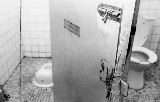 A rusted and poorly managed pit toilet (left) at Korean service plaza in 2003. The door is broken and cracked. [KIM HYUN-JU]