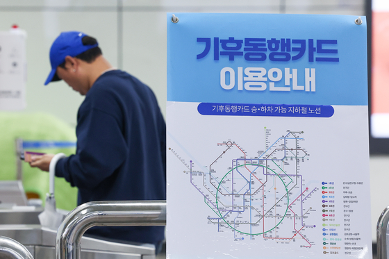 A person passes through the subway turnstiles at the platform at Gwanghwamun Station in central Seoul on April 15, with a banner advertising the Climate Card unlimited public transportation pass displayed nearby. [YONHAP]