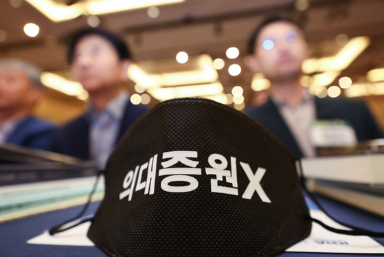 A black-colored face mask with a message saying ″No medical schools recruitment quota hike″ is placed on a table at a general assembly of the Korean Medical Association which was held in southern Seoul on Sunday. [YONHAP] 