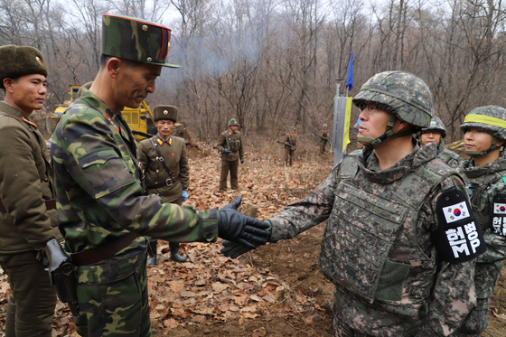North Korean and South Korean soldiers shake hands during a road construction project near the military demarcation line (MDL) in November 2018. [MINISTRY OF NATIONAL DEFENSE] 