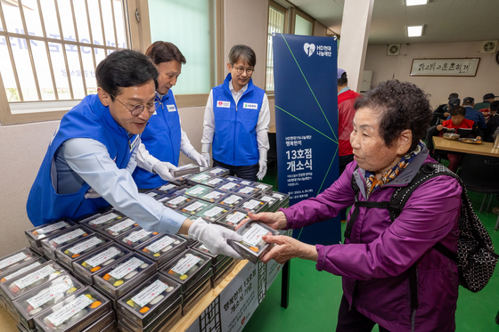 From left, Rep. Shin Yeong-dae of the Democratic Party, Gunsan Mayor Kang Im-jun and secretary general of HD Hyundai 1% Nanum Foundation Keum Seok-ho distribute commemorative rice cakes to local elders at the 13th Happy Plate opening ceremony in Gunsan, North Jeolla, on Tuesday. [HD HYUNDAI]