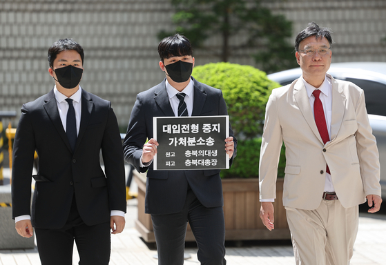 Two medical students, left, and their lawyer Lee Byeong-chul, right, file an injunction against the presidents of three national universities and the Korean Council for University Education at the Seoul Central District Court in Seocho District, southern Seoul, on April 22. [YONHAP]