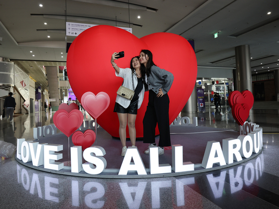 Foreign visitors take a photo of themselves in front of a heart-shaped art structure themed "Love is all around you" at Coex in southern Seoul on Wednesday. [YONHAP]