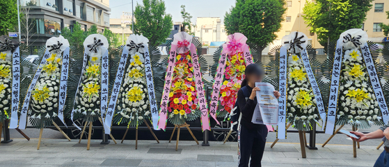 Wreaths of flowers displaying boy band BTS's fans' messages of disapproval with BigHit Music, the band's label, and its parent company's management are displayed in front of HYBE's headquarters in Yongsan District, central Seoul, on Friday.  [YONHAP]