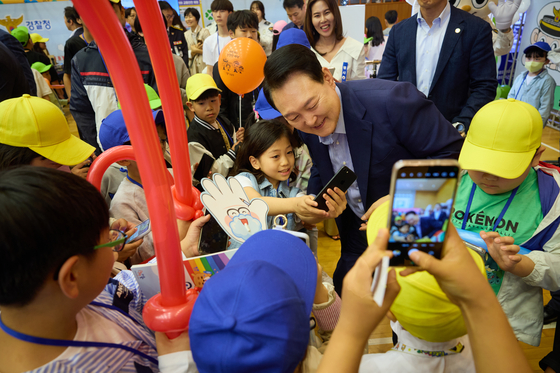 President Yoon Suk Yeol, center, takes a selfie with kids at an event to mark Children’s Day at the Blue House, the former presidential compound, in central Seoul, on Sunday. [PRESIDENTIAL OFFICE]