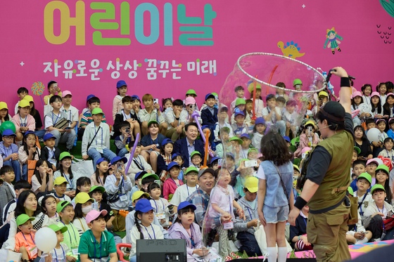 President Yoon Suk Yeol, center, and hundreds of kids and their parents watch a bubble magic show at an event to mark Children’s Day at the Blue House, the former presidential compound, in central Seoul, on Sunday. [PRESIDENTIAL OFFICE]