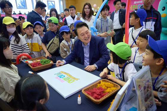 President Yoon Suk Yeol, center, makes a picture frame using air purifying plants with kids at the Blue House, the former presidential compound, in central Seoul on Sunday at an event to mark Children’s Day. [PRESIDENTIAL OFFICE]