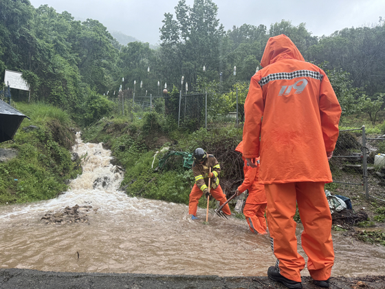 Fire authorities clear drains after receive a report of a drain clog due to the heavy rain in Suncheon, South Jeolla, on Sunday. [South Jeolla Fire Services Headquarters]