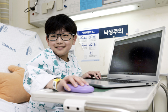 A 10-year-old boy with a rare disease, Yoon San, smiles and shows off some computer coding he did on Thursday at Seoul National University Hospital in central Seoul. [JANG JIN-YOUNG]