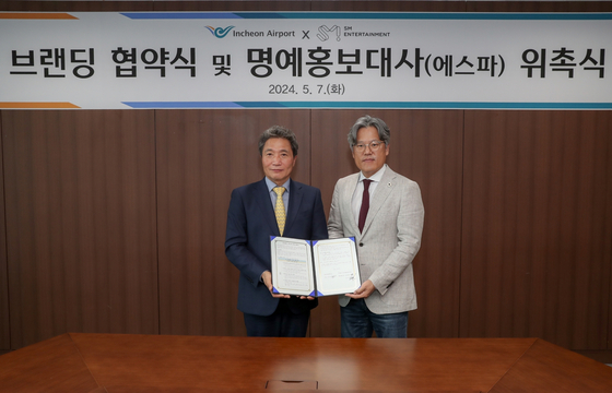 President Lee, left, and CEO of SM Entertainment, Jang Cheol-hyuk, pose for photos after signing a branding deal on Tuesday to rebrand the Incheon Airport with ″a major digital transformation" through the power of K-pop. [SM ENTERTAINMENT]