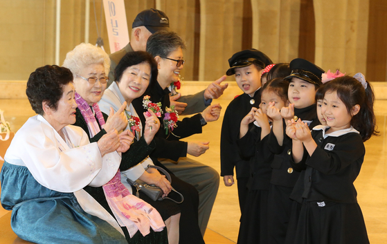 Children from the Gu-am Pani Pani Daycare Center make finger hearts after presenting older adults with carnations at the La Domus Art Center in Yuseong District, western Daejeon, on Tuesday, the day before Parents’ Day. [NEWS1]