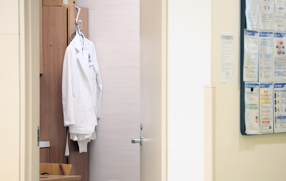 A doctor's white gown hangs on a closet in a general hospital in Seoul on Tuesday. [YONHAP] 