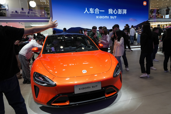 Visitors look at a Xiaomi SU7 car on display during the Auto China 2024 in Beijing on April 28, 2024. [AP/YONHAP]