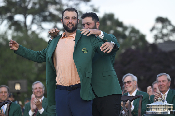 The 2023 Masters Champion Jon Rahm of Spain, puts on the green jacket of the 2024 Champion, Scottie Scheffler, after the final round of Masters Tournament at Augusta National Golf Club in Augusta, Georgia on April 14. [GETTY IMAGES]