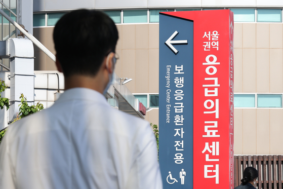A medical professional stands in front of a vertical signboard indicating the direction to the emergency room at a general hospital in downtown Seoul on Wednesday. [NEWS1] 