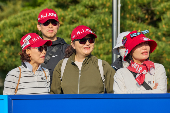 Spectators wearing red caps saying “H. J. Kim,” watch the Aramco Team Series presented by Public Investment Fund at the New Korea Country Club in Goyang, Gyeonggi on Friday. [ARAMCO TEAM SERIES]