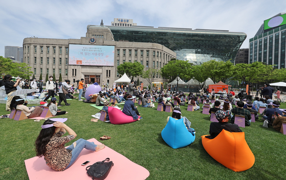 People sit and read books at the Seoul Outdoor Library installed in Seoul Plaza, central Seoul. [YONHAP]