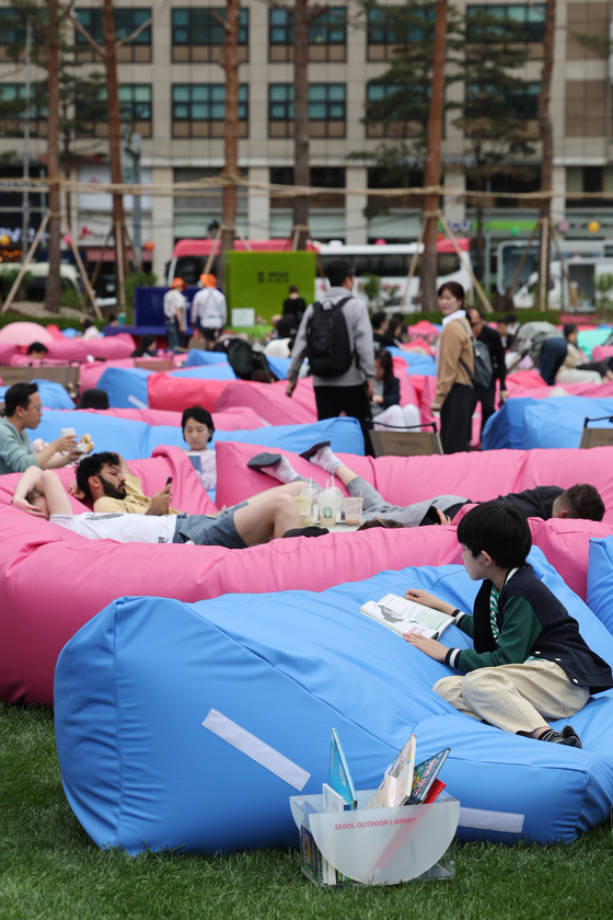 Visitors of Seoul Outdoor Library in central Seoul enjoy their afternoon reading on the bean bags on Seoul Plaza. [YONHAP]