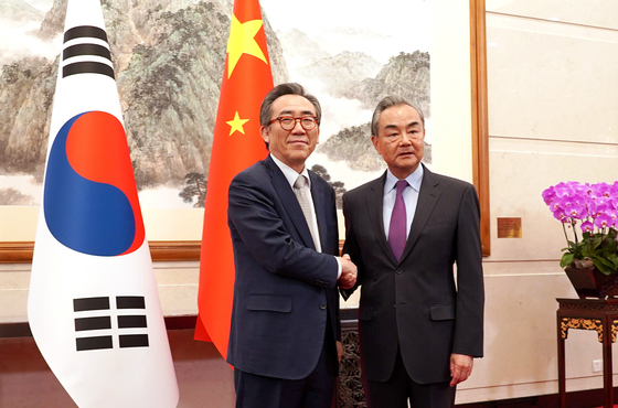 South Korean Foreign Minister Cho Tae-yul, left, and his Chinese counterpart Wang Yi shake hands during a meeting in Beijing on Monday. [NEWS1]