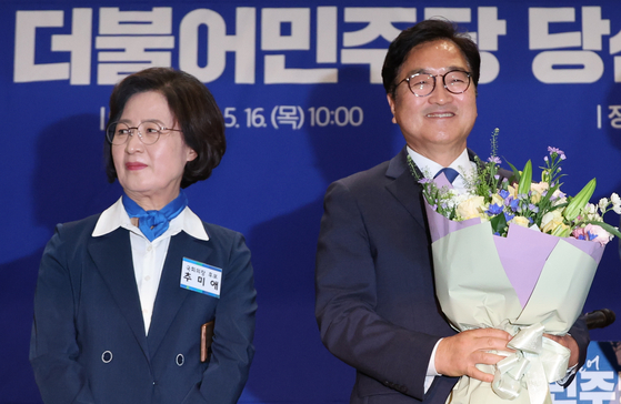 Five-term lawmaker Woo Won-shik, right, holds a bouquet at the National Assembly in Yeouido, western Seoul, after winning the liberal Democratic Party's contest to select a candidate to take up the speakership of upcoming legislature. His competitor Choo Mi-ae stands on the left. [YONHAP]