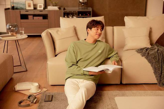 Actor Gong Yoo sits on the floor using the sofa as a back rest. [ILOOM]