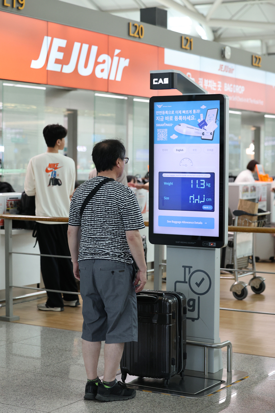 A passenger of Jeju Air, a budget carrier, weighs a suitcase before checking it in at Incheon International Airport on Sunday. [YONHAP]