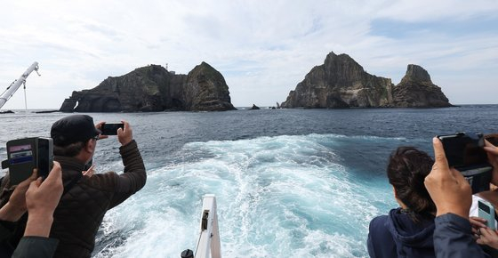 Visitors take photos of the Dokdo islets in a passenger ship that heads to the Dokdo islets. [NEWS1]