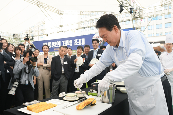 Presiden Yoon Suk Yeol, kanan, membuat telur gulung saat makan malam bersama korps pers di kompleks kantor kepresidenan Yongsan di pusat kota Seoul, Jumat. [PRESIDENTIAL OFFICE]