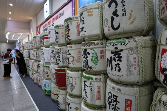 Visitors to the Seoul Sake Festival 2024 look at wooden containers of sake in southern Seoul on Sunday. The festival displays around 500 different types of premium sake. [YONHAP]