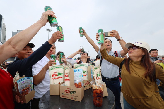 Tourists enjoy free beer and dakgangjeong (glazed chicken nuggets) during the 1883 McGang Party at Sangsang Platform in Jung District, Incheon, on Saturday. [YONHAP]