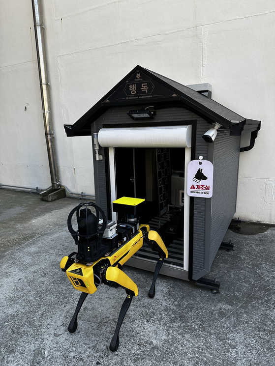 Pictured are a robot dog and its house. The dog patrols the factory six times a day, each time taking up to 50 minutes. After each patrol, it goes back to the house to charge. [SK INNOVATION]