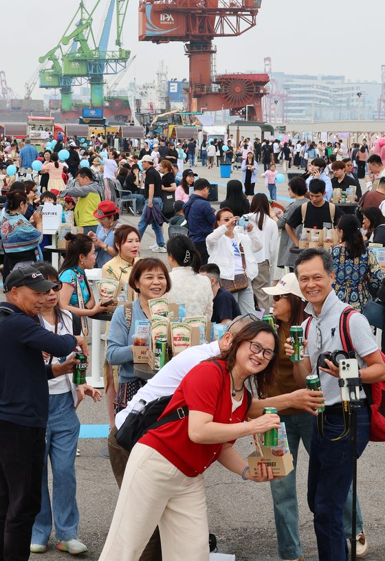  Tourists enjoy free beer and dakgangjeong (glazed chicken nuggets) during the 1883 McGang Party at Sangsang Platform in Jung District, Incheon, on Saturday. [YONHAP]