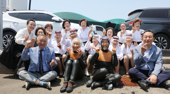 The retiring haenyeo, along with Kim Sung-geun, the chief of the Gwideok 2-ri fishing village association, left, Jung Young-ae, the head of the haenyeo association, and Yang Young-cheol, the chief director of Jeju Free International City Development Center, right, pose for a commemorative photo last Friday. [YONHAP]